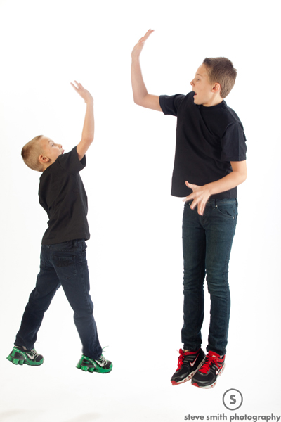 Two boys jump high-five one another