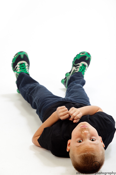Young boy lays upside down on studio floor